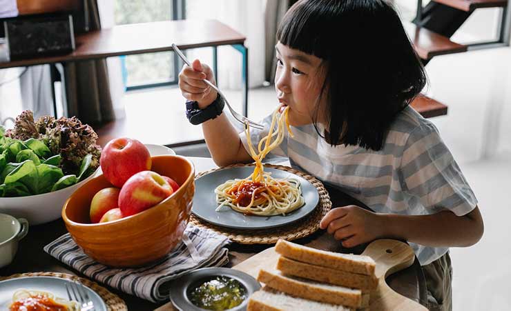 una bambina mangia spaghetti