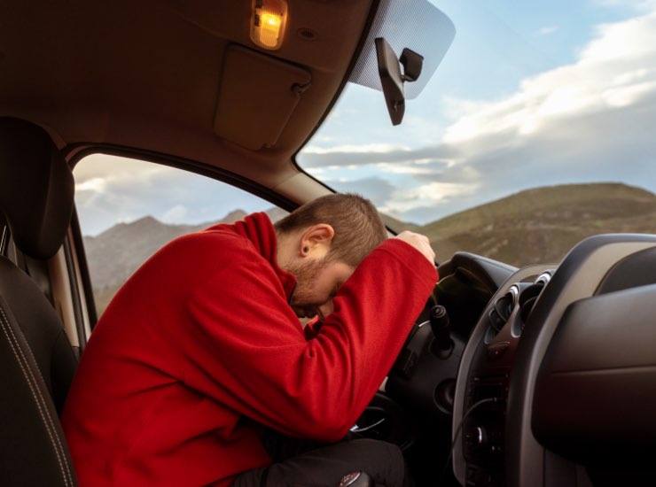 Un uomo dorme appoggiato al volante