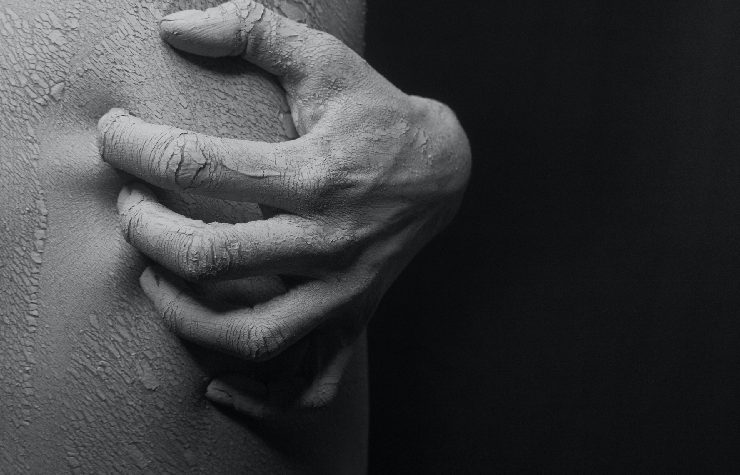 Una mano si prude la schiena in bianco e nero